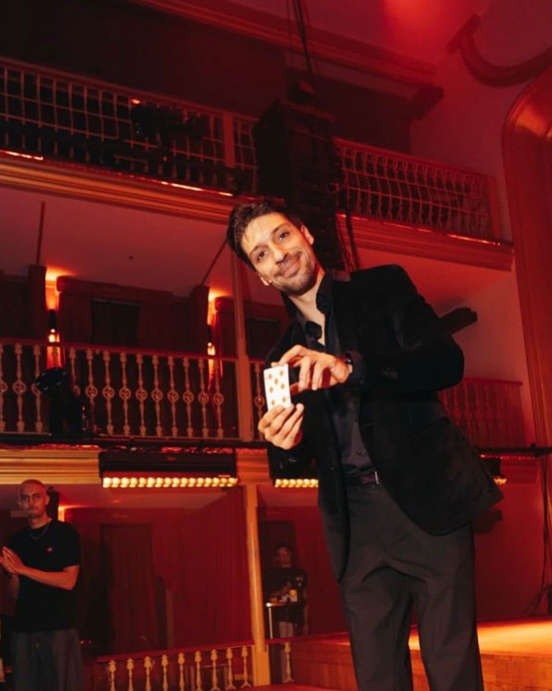 Lion in a theatre hall under red light, holding a deck of cards