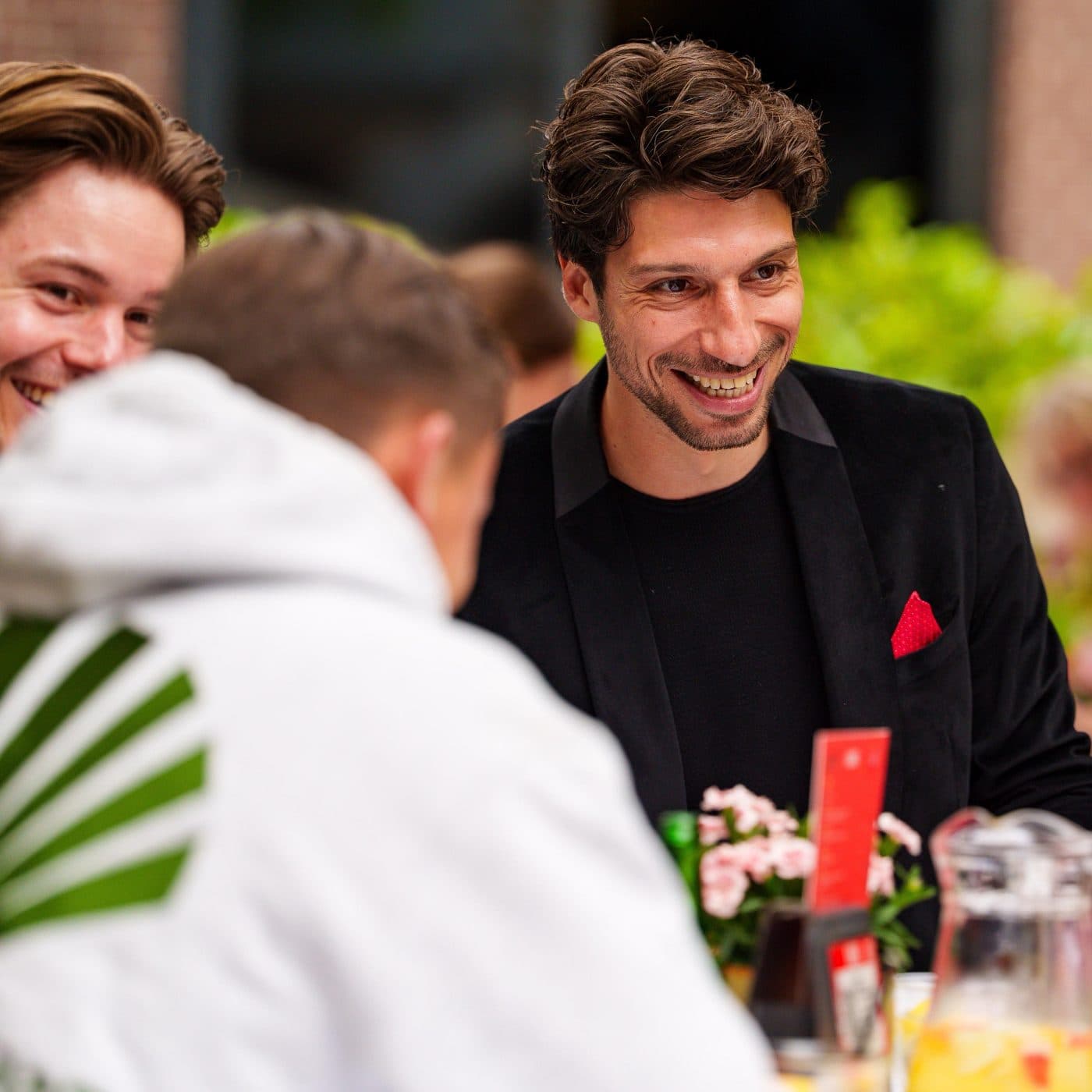 Guests at a terrace table laughing with Lion
