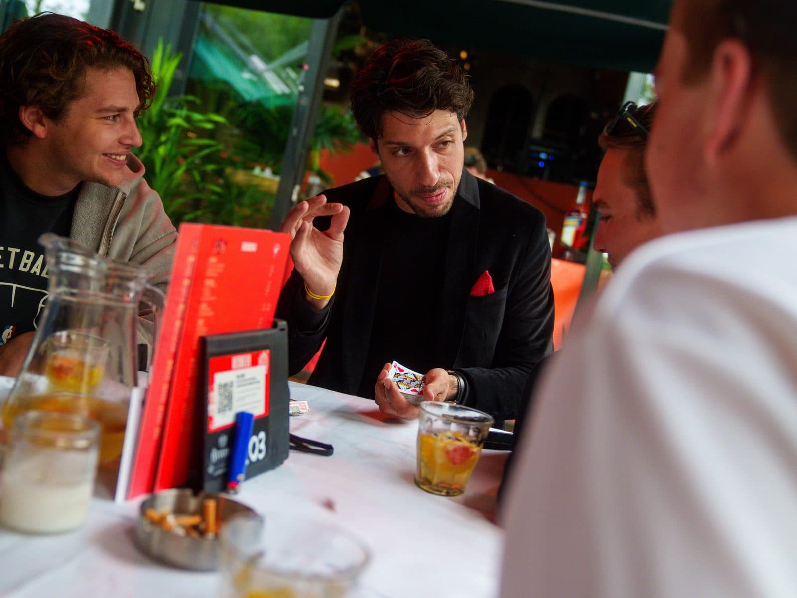 Lion at a table with guests, a deck of cards and drinks
